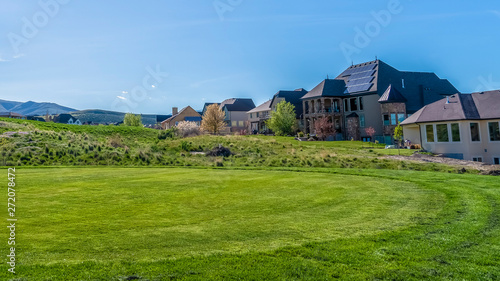 Panorama frame Residential houses on a terrain with vivid green grasses viewed on a sunny day
