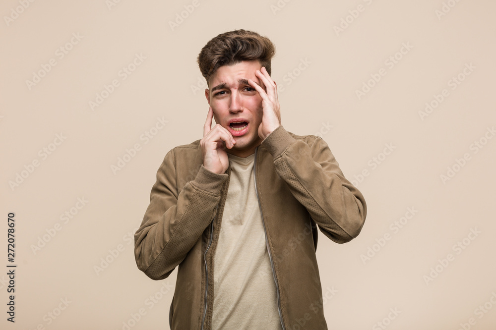Young caucasian man wearing a brown jacket whining and crying disconsolately. Young caucasian man wearing a brown jacket whining and crying disconsolately.