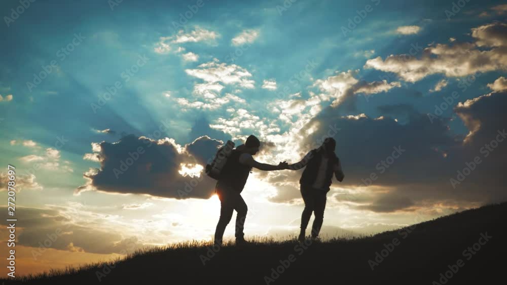 The Silhouette of two man on the top of mountain with Backpacks and other Gear expressing Energy and Happiness. Two tourist young men on rocky cliff and enjoying view. Travel concept. The Silhouette of two man on the top of mountain with Backpacks and other Gear expressing Energy and Happiness. Two tourist young men on rocky cliff and enjoying view. Travel concept.