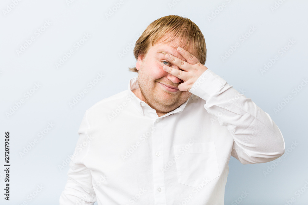 Young authentic redhead fat man blink at the camera through fingers, embarrassed covering face. Young authentic redhead fat man blink at the camera through fingers, embarrassed covering face.