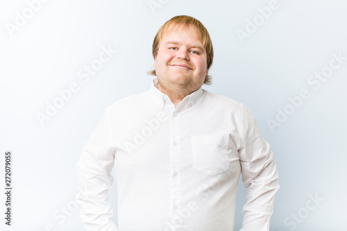 Young authentic redhead fat man happy, smiling and cheerful.