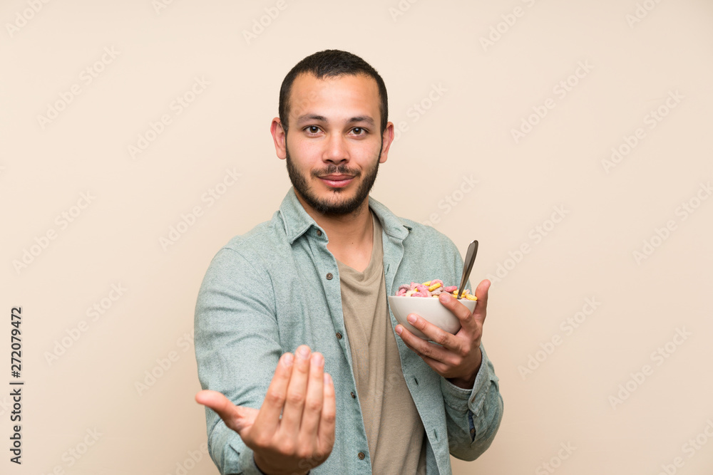 Colombian man with bowl of cereals presenting and inviting to come Colombian man with bowl of cereals presenting and inviting to come