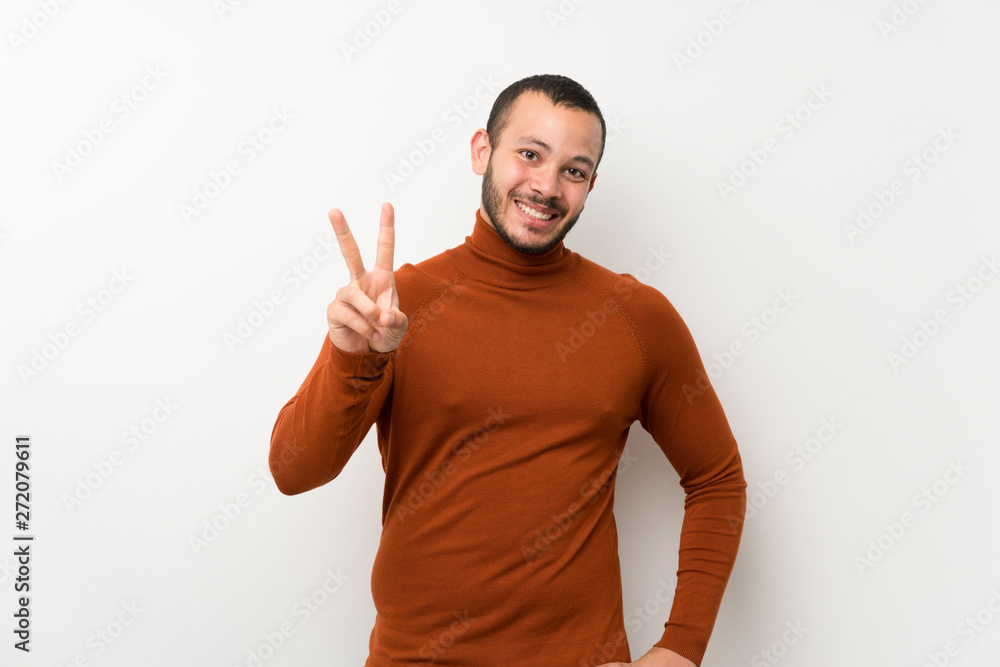 Naklejka premium Colombian man with turtleneck sweater smiling and showing victory sign