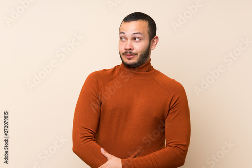 Colombian man with turtleneck sweater making doubts gesture looking side
