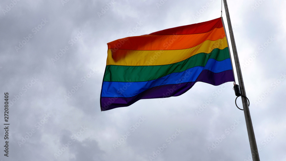 LGBT rainbow pride flag waving at wind on cloudy british sky background in northampton england LGBT rainbow pride flag waving at wind on cloudy british sky background in northampton england