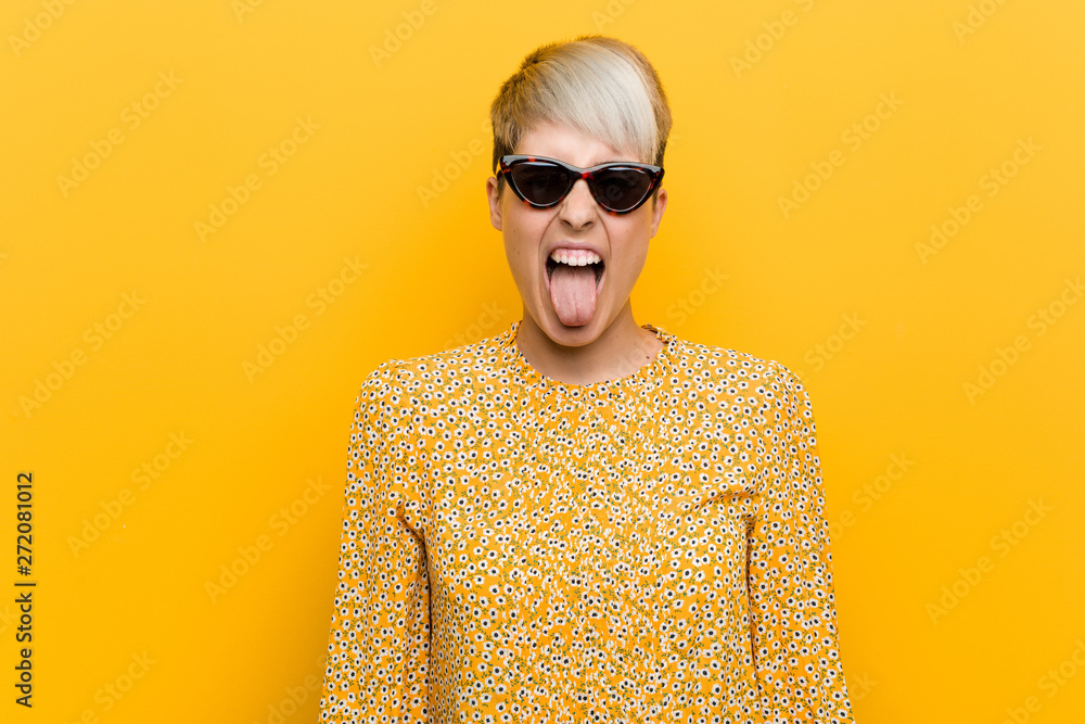 Young curvy woman wearing a floral summer clothes funny and friendly sticking out tongue. Young curvy woman wearing a floral summer clothes funny and friendly sticking out tongue.