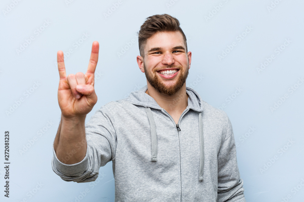 Fototapeta premium Young handsome fitness man showing a horns gesture as a revolution concept.