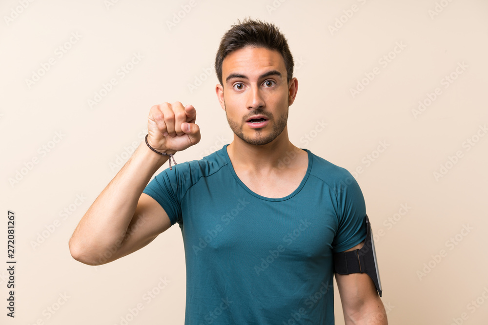 Handsome sport man over isolated background surprised and pointing front Handsome sport man over isolated background surprised and pointing front