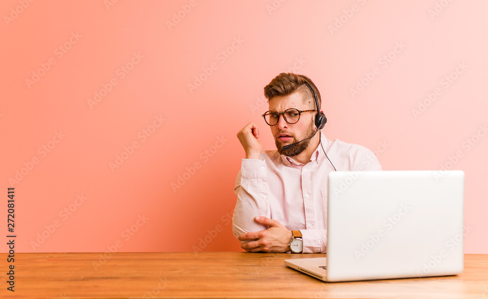 Young man working in a call center touching back of head, thinking and making a choice. Young man working in a call center touching back of head, thinking and making a choice.