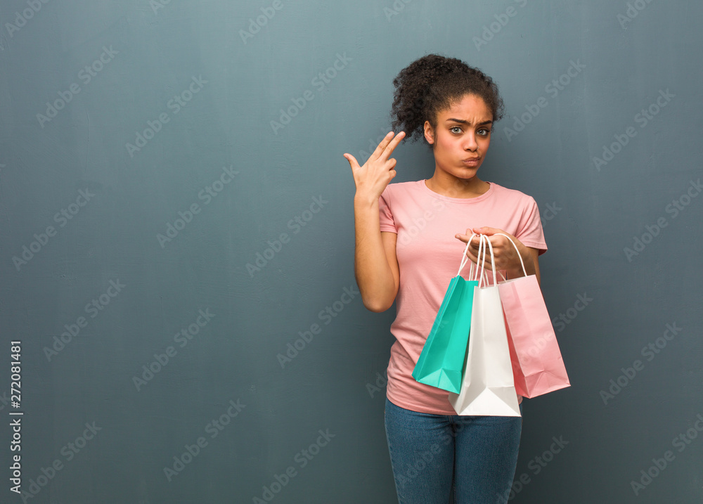 Young black woman doing a suicide gesture. She is holding a shopping bags.