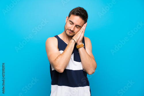 Schilderij op canvas Handsome young man over isolated background making sleep gesture in dorable expr