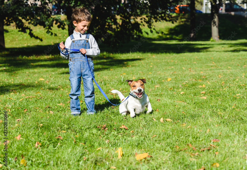 Cute boy looking at his playful dog trying to run away on leash Cute boy looking at his playful dog trying to run away on leash
