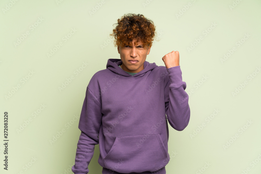 Young african american man over isolated green wall with angry gesture Young african american man over isolated green wall with angry gesture