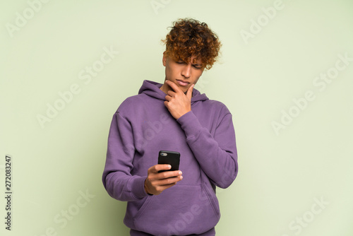 Young african american man over isolated green wall thinking and sending a message