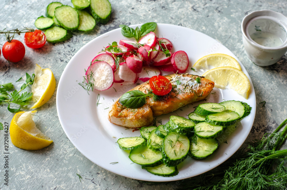 Salmon steak with lemon, tomatoes, cucumber and radish on a plate. Healthy seafood. Proper nutrition food. Salmon steak with lemon, tomatoes, cucumber and radish on a plate. Healthy seafood. Proper nutrition food.