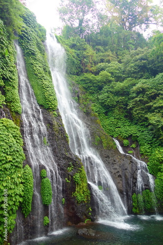 Jungle waterfall cascade in tropical rainforest with rock and turquoise blue pond. Its name Banyumala because its twin waterfall in mountain slope, Bali