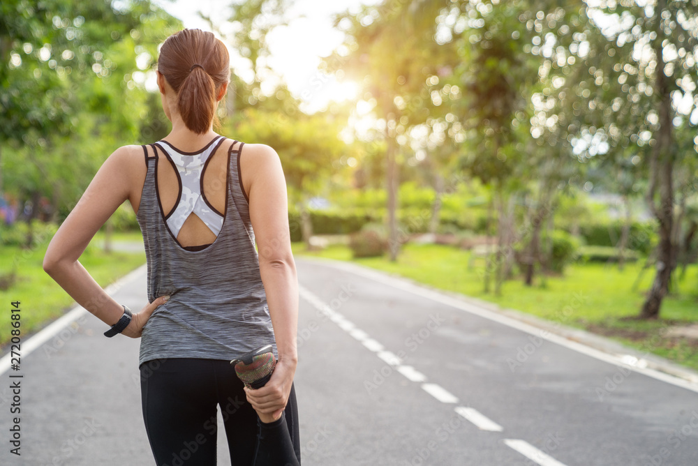 Woman runner warming up before running in park. Young fitness woman runner stretching legs before run on city. People and sport concept Woman runner warming up before running in park. Young fitness woman runner stretching legs before run on city. People and sport concept