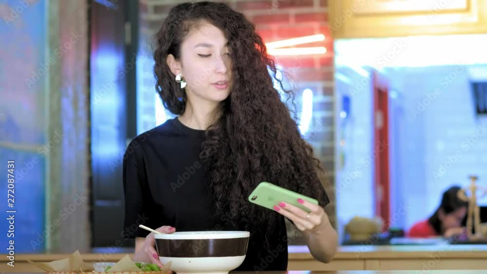 Beautiful asian woman taking selfies on a smartphone. Young asian girl take photo with pho soup at cafe shop. Chinese, Vietnamese or Japanese cafe or restaurant Beautiful asian woman taking selfies on a smartphone. Young asian girl take photo with pho soup at cafe shop. Chinese, Vietnamese or Japanese cafe or restaurant