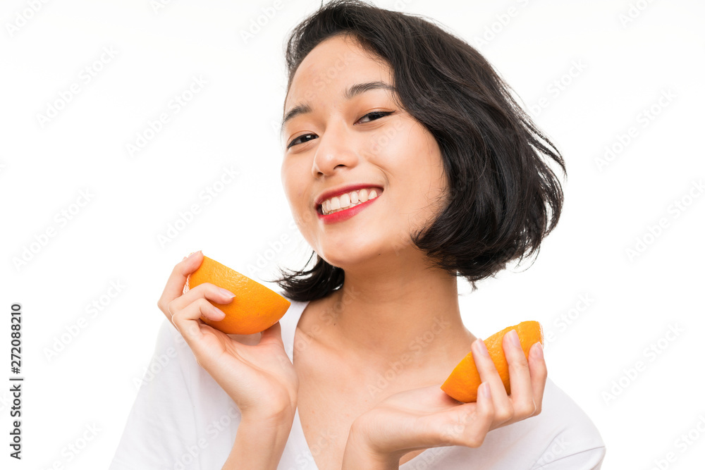 Asian young woman over isolated background holding an orange Asian young woman over isolated background holding an orange