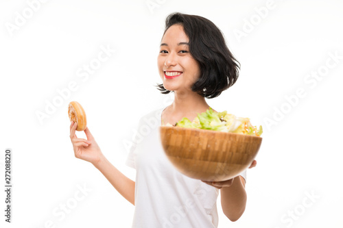 Fotografía Asian young woman over isolated background with salad and donut