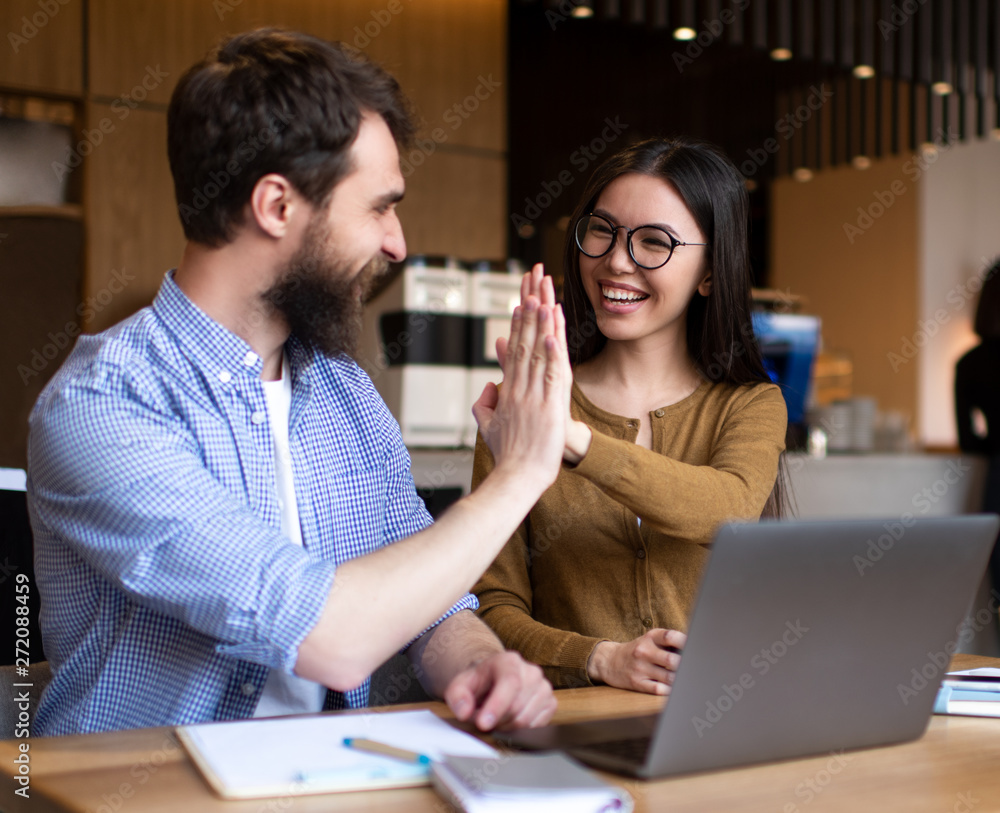 Fototapeta premium Business colleagues are motivated, giving high five and celebration successful deal. Cooperation Meeting Partnership Career growth Team building Successful business. Portrait of young happy developers