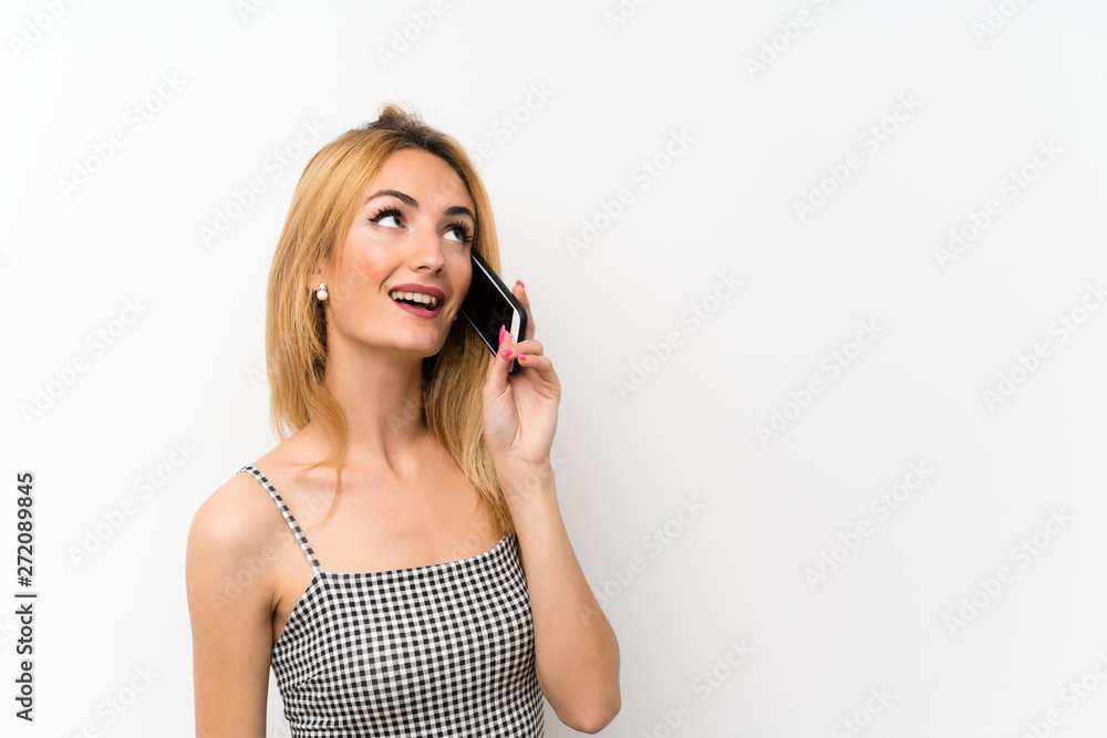 Young blonde woman over isolated white keeping a conversation with the mobile phone Young blonde woman over isolated white keeping a conversation with the mobile phone