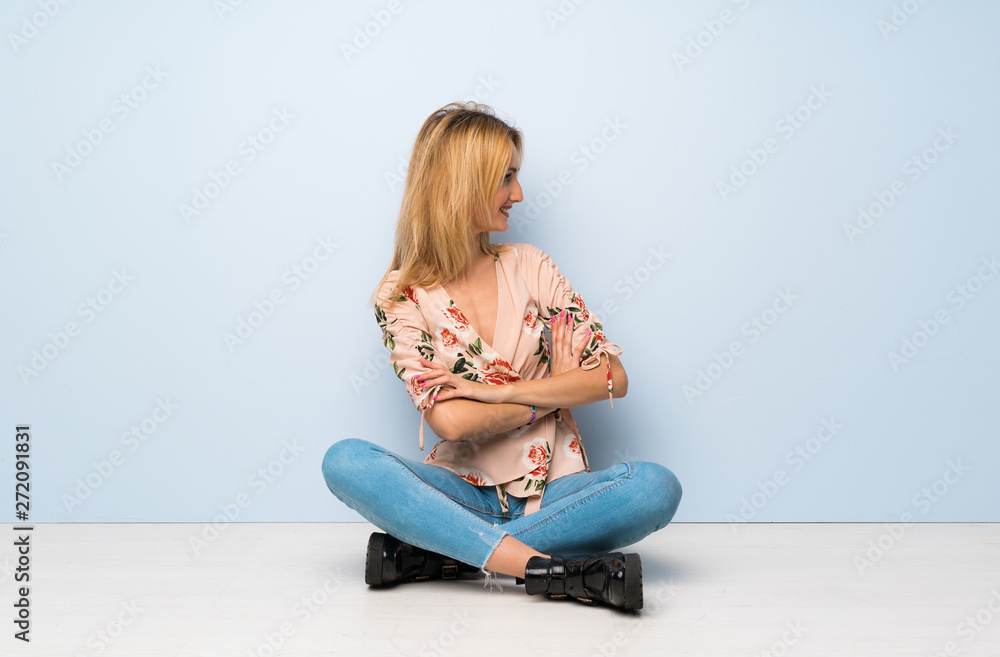 Fototapeta premium Young blonde woman sitting on the floor in lateral position