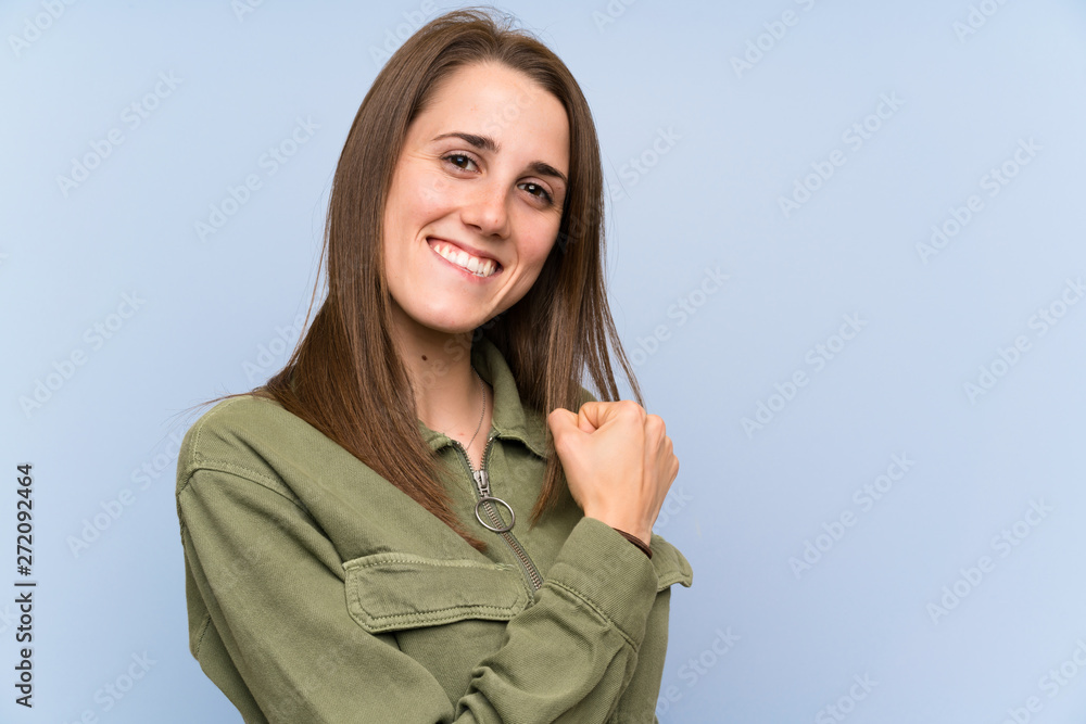 Young woman over isolated blue wall celebrating a victory Young woman over isolated blue wall celebrating a victory