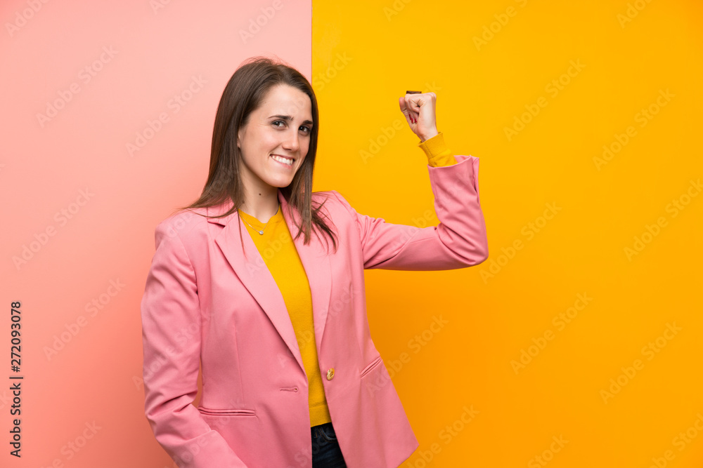 Young woman with pink suit over colorful background making strong gesture Young woman with pink suit over colorful background making strong gesture