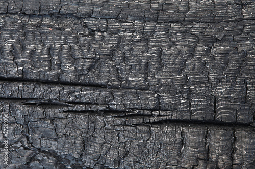 Scorched wood texture. Burned wood structure background. Burnt timber surface backdrop. Wooden burn-off closeup shot. Old burnt wooden beam. Firebrand surface image. Charred coarse-textured timber. photo