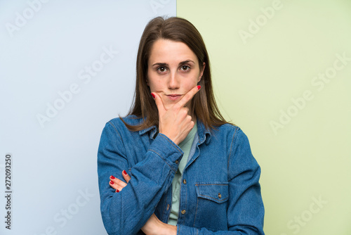 Young woman over colorful background standing and thinking an idea