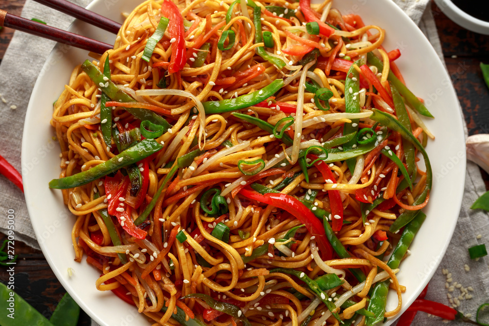 Chow mein, noodles and vegetables dish with wooden chopsticks Chow mein, noodles and vegetables dish with wooden chopsticks