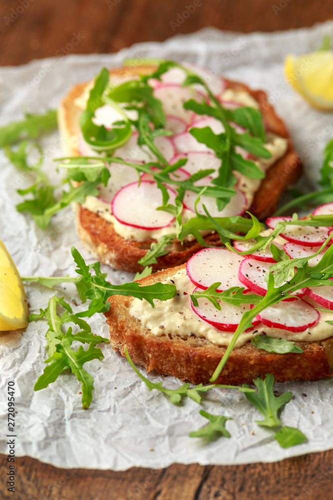 Hummus sourdough toast with reddish and wild rocket. Healthy vegan food Hummus sourdough toast with reddish and wild rocket. Healthy vegan food