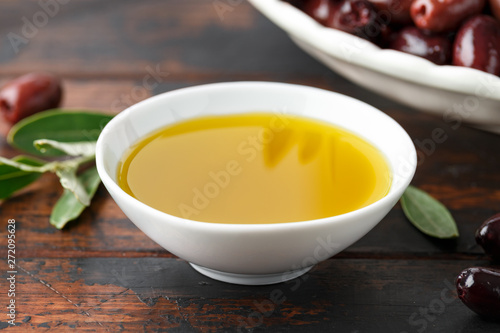 Extra virgin olive oil and kalamata olives on rustic wooden background