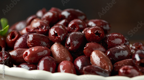 Pitted kalamata olives in bowl on rustic wooden background photo