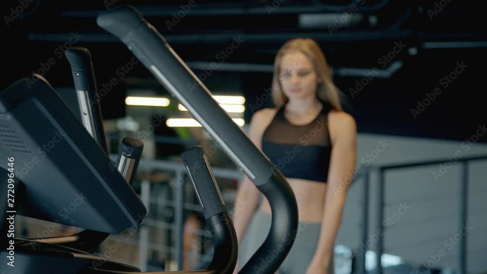 Lady making workout on orbitrek in gym Lady making workout on orbitrek in gym