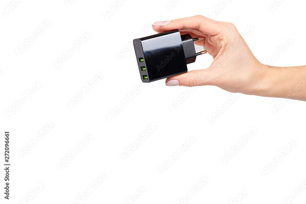 Hand with black USB wall chrger plug, three ports. Hand with black USB wall chrger plug, three ports.