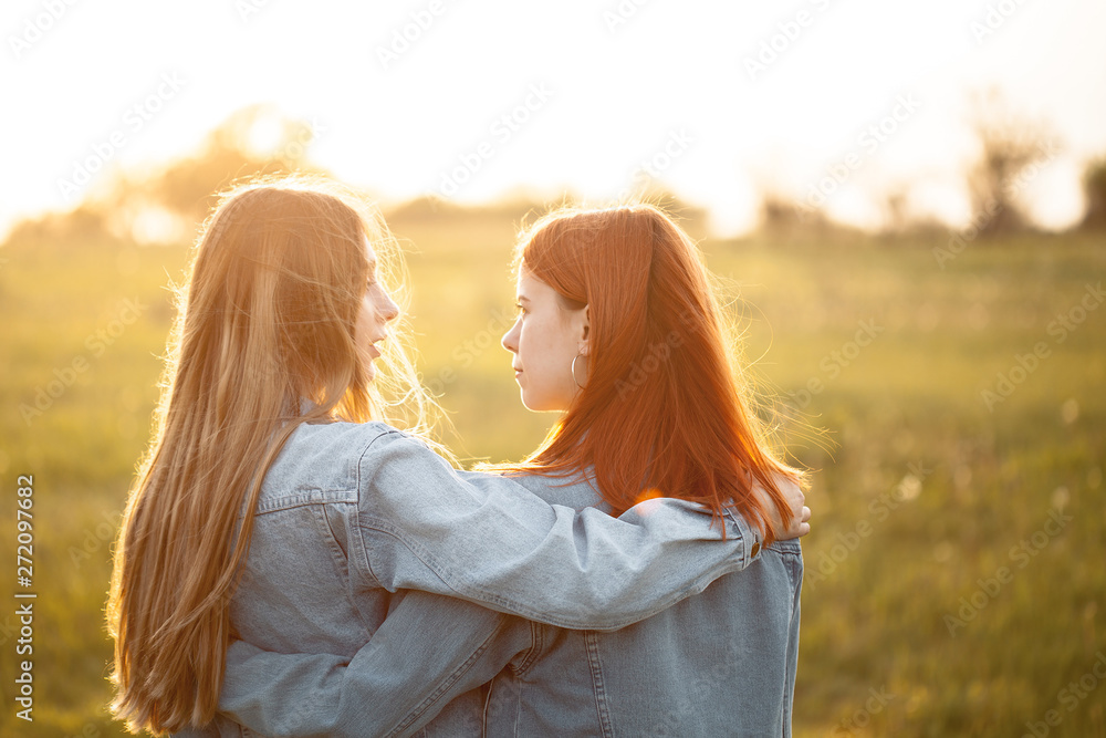 Fototapeta premium Two young women standing together under sunset. Best friends