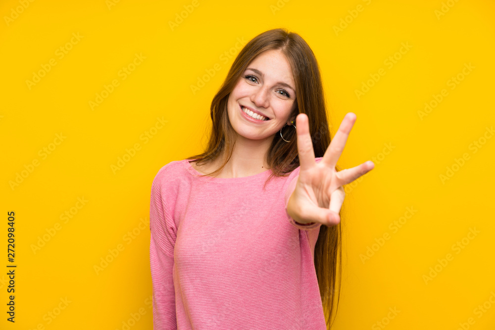Young woman with long hair over isolated yellow wall happy and counting three with fingers Young woman with long hair over isolated yellow wall happy and counting three with fingers