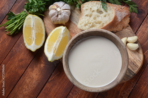 Tahini sauce made from sesame seeds in bowl with parsley on wooden background