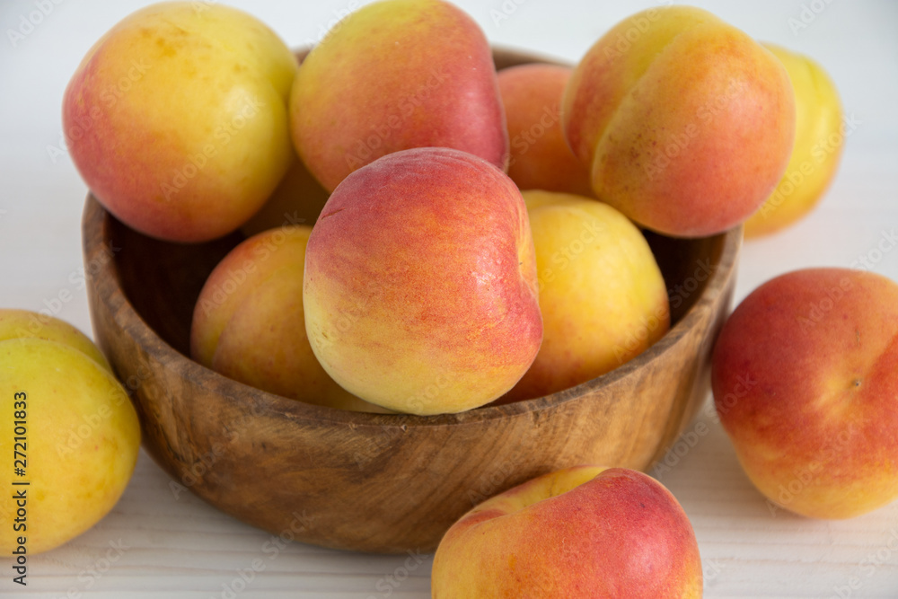 Close-up of apricots in wooden bowl on white wooden background Close-up of apricots in wooden bowl on white wooden background