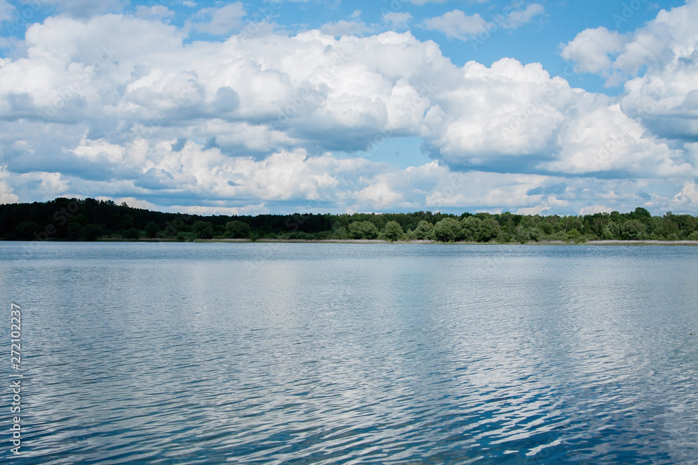 white clouds on a blue sky on a Sunny summer day forest shore