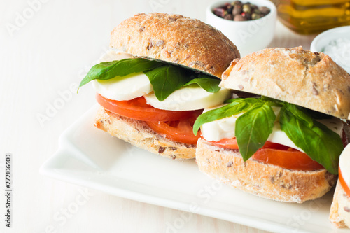 Close-up photo of sandwich, burger with caprese salad with ripe tomatoes, basil, buffalo mozzarella cheese. Italian and Mediterranean food concept. Fresh and healthy organic meal. 
