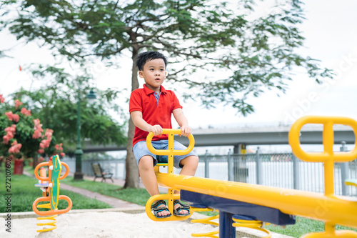 Happy little boy on seesaw outdoors