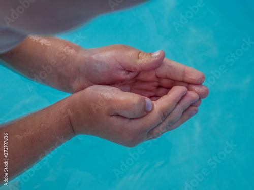 Hands close up. Little blonde boy in hot summer day swim in carcas pool in swimwear for boys.