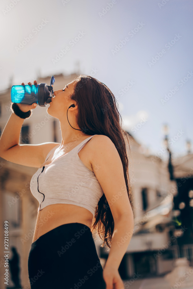 Attractive athletic woman relaxing after workout with shaker