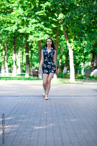 Young beautiful woman in a blue short dress walking on the road