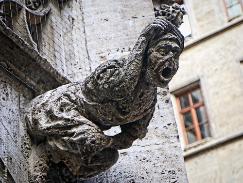 A waterspout gargoyle representing a witch on the building facade of the neo-Gothic courtyard of the city hall of Munich, Germany photo