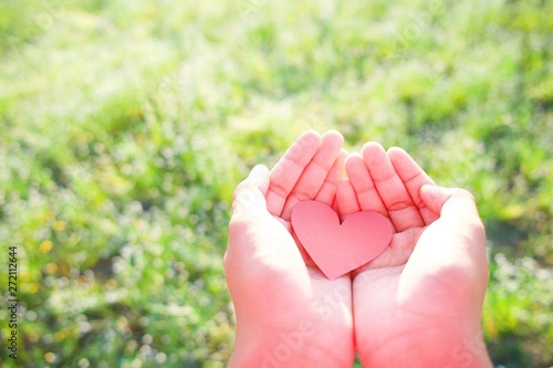 Red heart put on finger with backgroundof field grass. photo