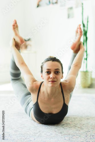 Young attractive smiling woman practicing yoga in a stylish room photo